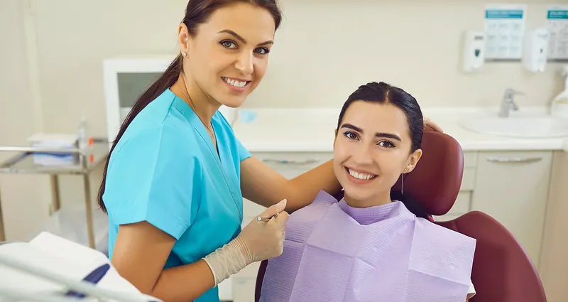 Odontóloga sonriendo junto a una paciente en el consultorio