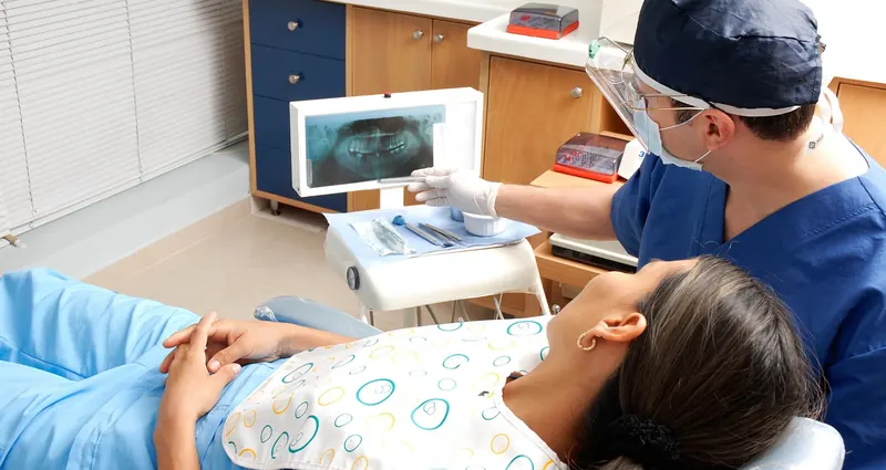 Dentista revisando una radiografía dental en pantalla durante un tratamiento